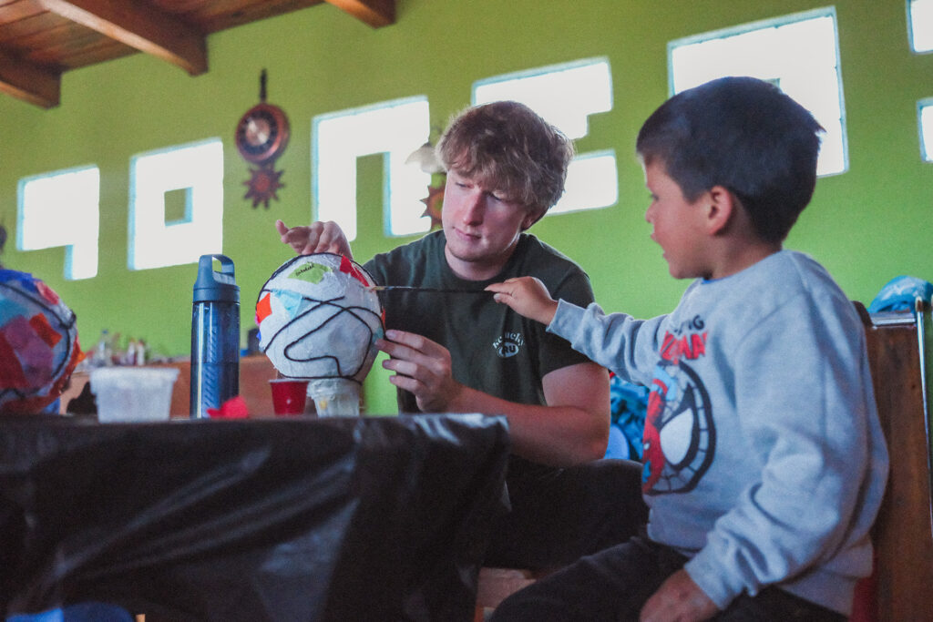 Opal House Summer 25 Preschool Workshop assistant Carter Brown helping a student.